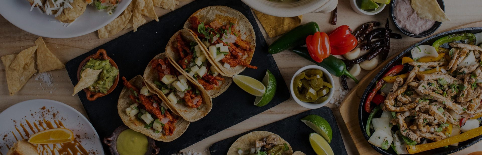 Mexican spread of tacos, fajitas and salsas on a wooden table